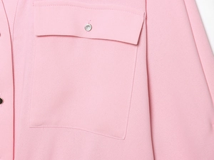 Détail du chemisier rose avec poche poitrine et fermeture par bouton en métal argenté