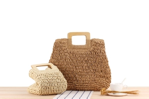 Détails des sacs cabas en paille tissée main avec poignées carrées en bois sur table