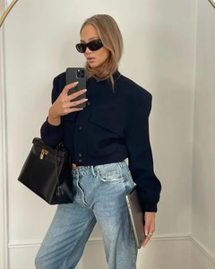 Fashionable dark blue slim-fit jacket paired with light blue jeans and black handbag
