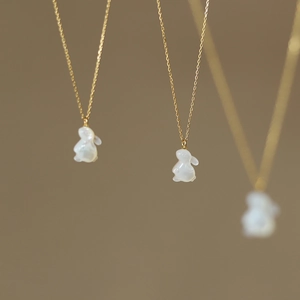 Détail d'un pendentif lapin en nacre blanche sculptée sur une chaîne dorée fine