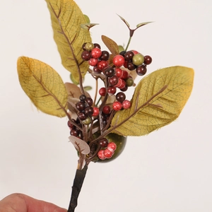 Detail of artificial Halloween autumn stems with red and green berries and maple leaves
