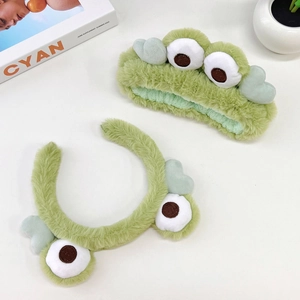 Detailed view of plush green frog headbands showing soft texture and embroidered eyes