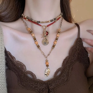 Detail of layered bohemian necklace with wooden beads and golden hammered pendant
