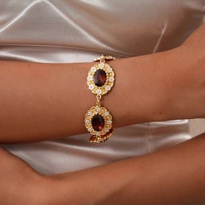 Detailed close-up of a vintage court style gold bracelet with deep red oval gems