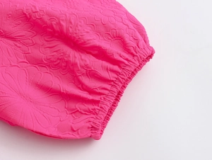 Macro shot of rose red floral embossed fabric with elasticated cuff details on dress