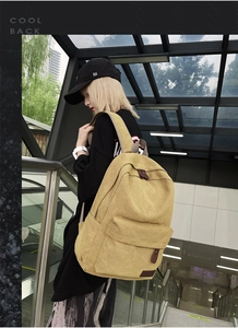 Close-up of canvas backpack front pocket with premium leather zipper pull and patch detail