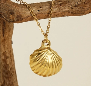 Detailed close-up of a golden shell pendant necklace displayed on a wooden branch branch