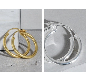 Macro detail of minimalist S925 sterling silver hoop earrings in gold and silver finish