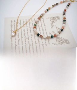 Close-up of handmade agate beaded necklace and gold wire wrapped pearl pendant jewelry