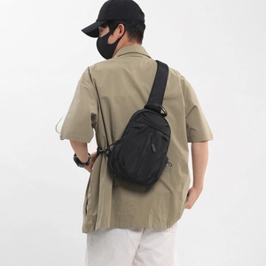 Men's black Oxford fabric chest bag shown on model with adjustable strap back view