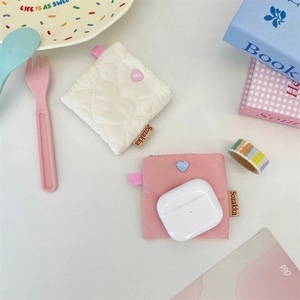 Detail of quilted heart earphone pouch showing AirPods storage in soft pink and beige colors