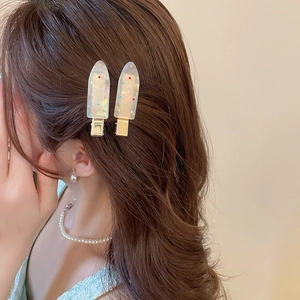 Close-up of two cream ice cream hair clips with colorful rhinestones on brown hair