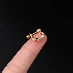Macro shot of 20G gold wave cartilage stud with clear zircons held on a fingertip