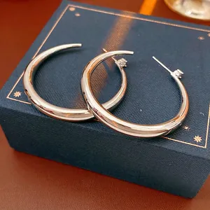 Minimalist silver-plated C-shaped earrings with zircon accents on a premium display