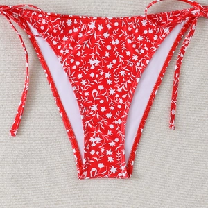Macro detail of red floral bikini bottoms with side ties and premium fabric texture