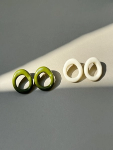 Artistic layout of geometric resin hoop earrings with elegant shadows on neutral surface