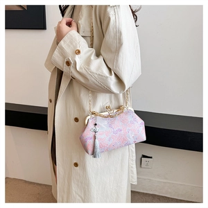 Detail of elegant embroidered evening clutch bag with butterfly clasp and tassel.