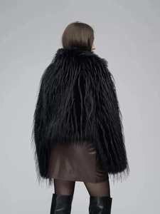 Back view of a luxury thick black faux fur coat for women styled with high boots