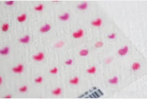 Close-up of 5D gradient pink heart nail art stickers on a textured white background