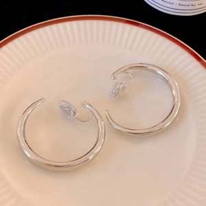 Silver vintage C-shape clip-on earrings with silicone pads on a ceramic tray