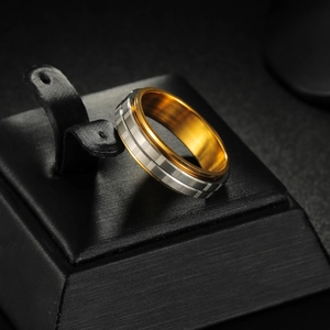 Close-up of dual-tone rotating titanium steel ring with silver and gold grooved texture