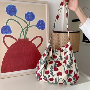 Close-up of canvas shoulder bag featuring red floral print in an artistic lifestyle setting