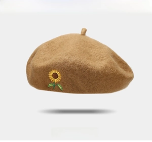 Close-up of a brown wool beret featuring detailed yellow sunflower embroidery detail