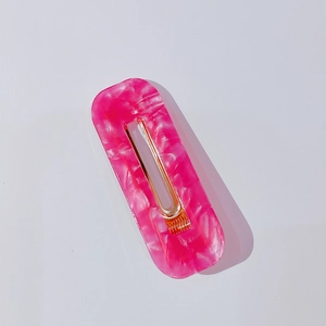 Détail de la barrette à cheveux en acétate marbré rose avec clip en métal doré