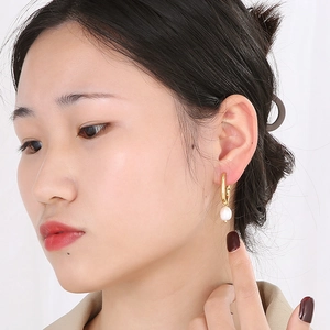 Close-up of pearl drop hoop earring on a model showing elegant gold and white details