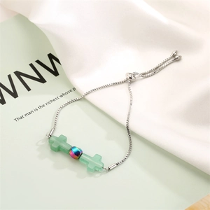 Detail of adjustable cross bracelet with light green onyx stones on silk background