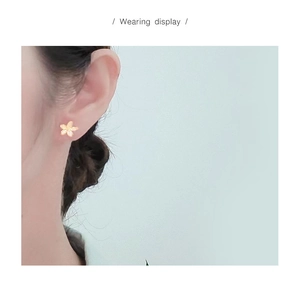 Close-up of elegant gold flower stud earrings with micro-inlaid crystals on earlobe