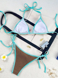 Flat lay of a two-piece bikini with white halter top and brown tie-side bottoms on white sand