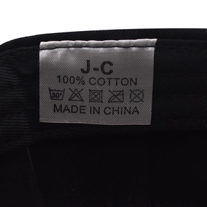 Detail of 100% cotton washing label with care instructions on a black baseball cap
