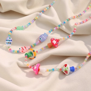 Détail du collier de perles avec champignons colorés et pendentifs poissons sur tissu