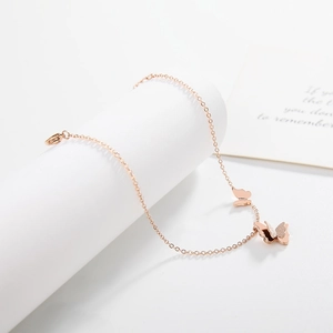 Elegant rose gold butterfly pendant necklace displayed on a white cylindrical stand