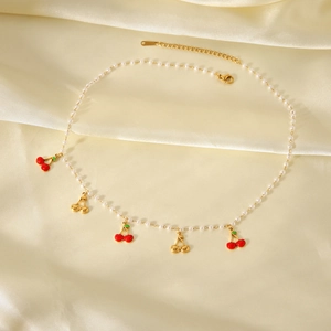 Collier cerise dorée avec perles et émail rouge sur fond en satin clair élégant