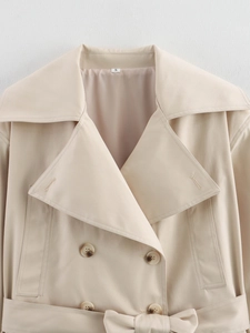 Gros plan d'un trench-coat kaki avec large revers, boutonnage croisé et ceinture à la taille