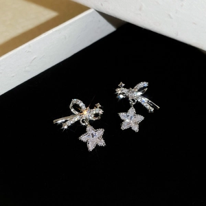 Macro shot of silver bow and star stud earrings with sparkling zircons in a gift box