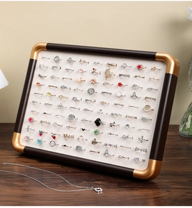 Detail of walnut wood ring display tray with gold corners and white velvet velvet padding