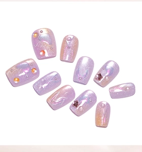 Macro detail of purple cat-eye press-on nails with 3D pearls and metallic stars