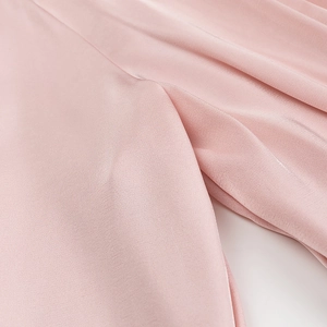 Macro shot of pink silk fabric detail showing smooth texture and elegant pleat draping