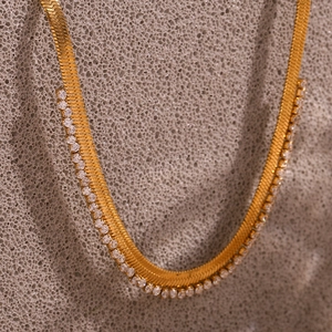 Detailed close-up of a gold-plated herringbone necklace with micro-pave cubic zirconia