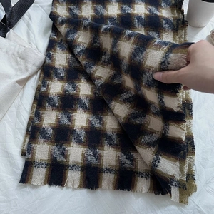 Close-up of houndstooth scarf texture with warm fringe detail in brown and black