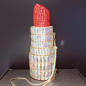 Detail of creative lipstick-shaped evening bag featuring red and iridescent rhinestones