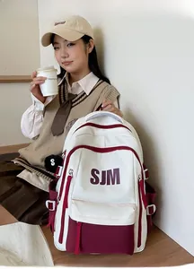 Detail of college style backpack with SJM logo, side pocket and plush charm on the strap