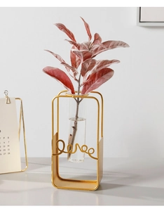 Detail of a gold metal frame tube vase featuring a love script ornament for home decor