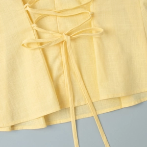 Détail du laçage et de la texture en lin sur un haut d'été jaune pâle élégant