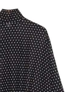 Detailed view of the sheer black polka dot fabric and high neckline on this fashion blouse
