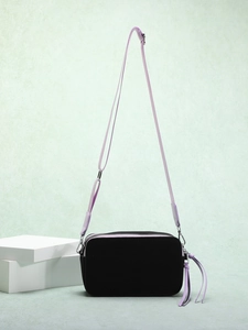 Detail view of black crossbody camera bag featuring purple strap and long tassel zipper