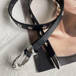 Fashionable black belt with silver floral cutout decorations and horseshoe buckle on fabric